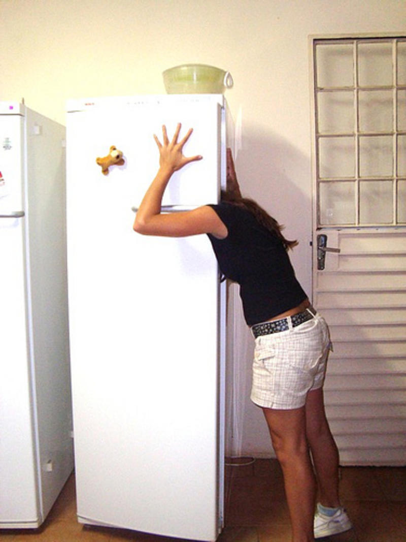 Пирсингованная неформалка с дредами стоит возле холодильника без трусов и лифчика